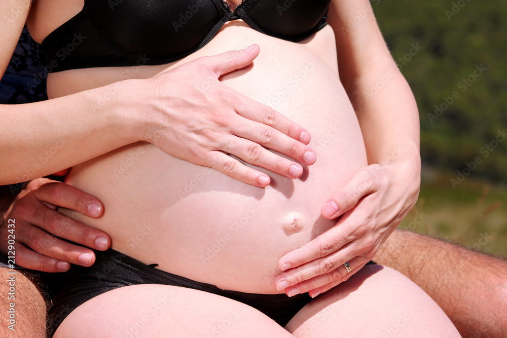 Hands of future parents is embracing and hugging on pregnant belly. Pretty pregnant  woman hug with her husband. Waiting of baby. Pregnancy, abdomen,  motherhood. Happy family concept, love, happiness. Stock Photo