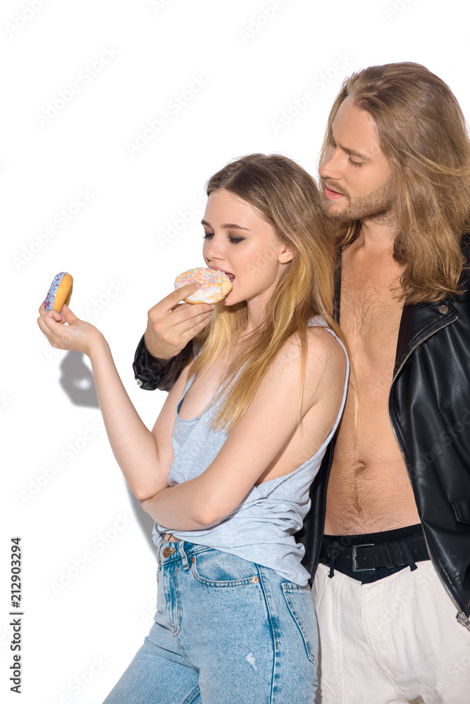 stylish young couple eating tasty donuts on white stylish young couple eating tasty donuts on white