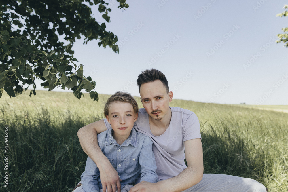 Portrait of young man embracing boy at a field Portrait of young man embracing boy at a field