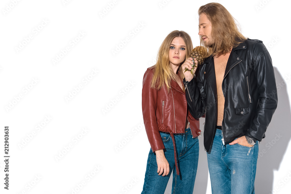 attractive young couple in leather jackets with pineapple standing together on white attractive young couple in leather jackets with pineapple standing together on white