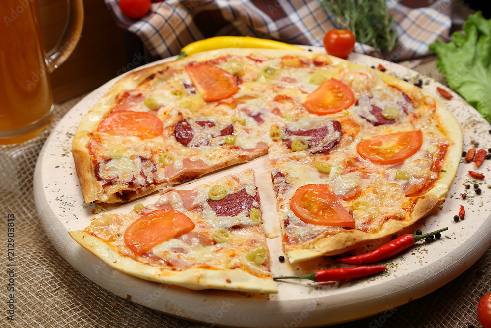 Pizza with tomato, cheese, smoked sausage, boiled sausage, pepper spices on a wooden tray close-up