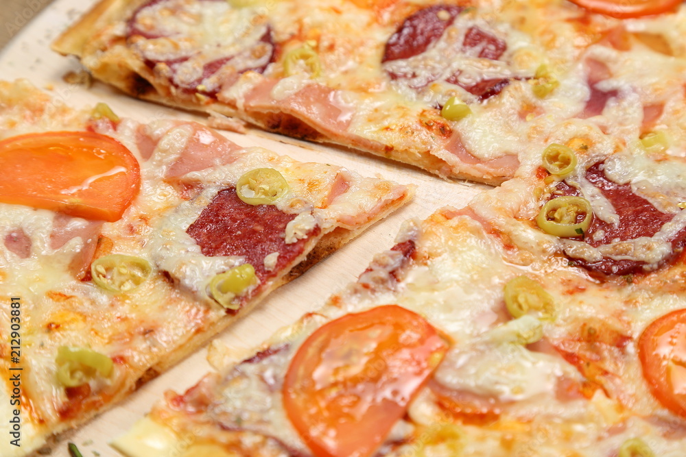 Pizza with tomato, cheese, smoked sausage, boiled sausage, pepper spices on a wooden tray close-up