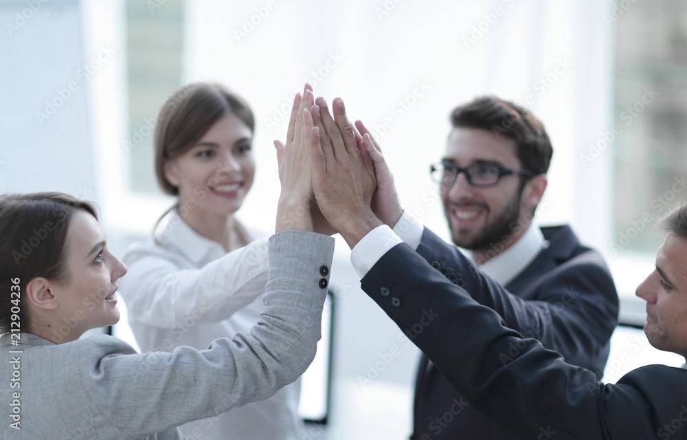 successful business team giving each other a high-five, standing in the office successful business team giving each other a high-five, standing in the office