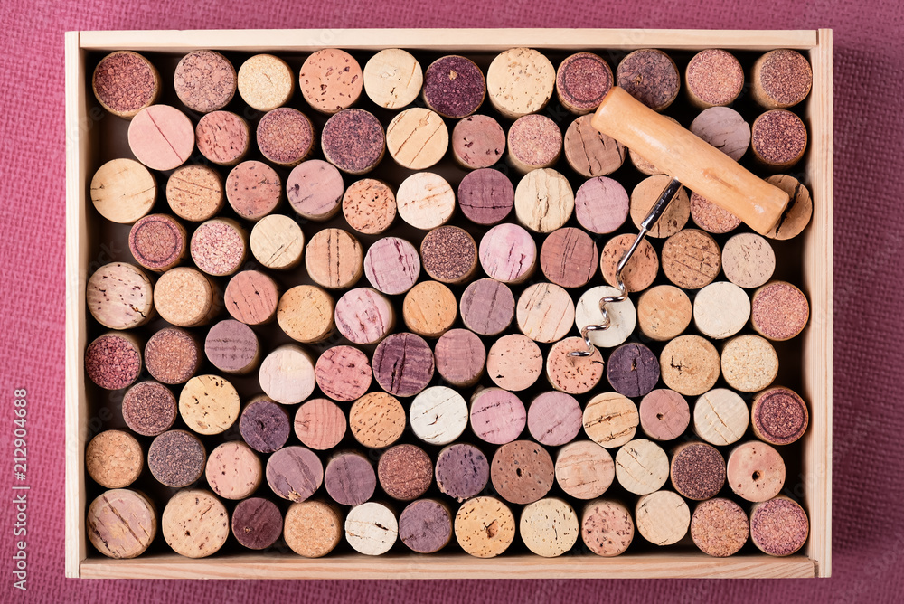 Wine cork stoppers in wooden box and corkscrew on Fuchsia background Copy space Wine cork stoppers in wooden box and corkscrew on Fuchsia background Copy space
