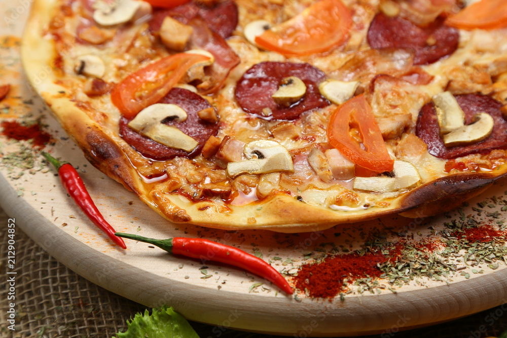 Pizza with mushrooms, tomato, smoked sausage, bacon, red pepper and cheese close-up Pizza with mushrooms, tomato, smoked sausage, bacon, red pepper and cheese close-up