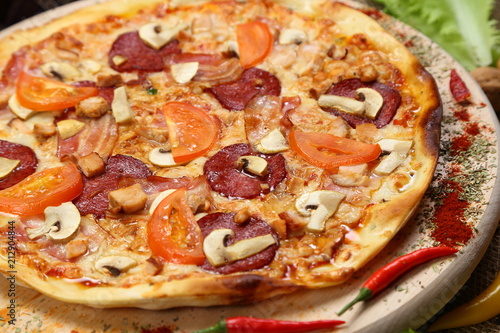 Pizza with mushrooms, tomato, smoked sausage, bacon, red pepper and cheese close-up