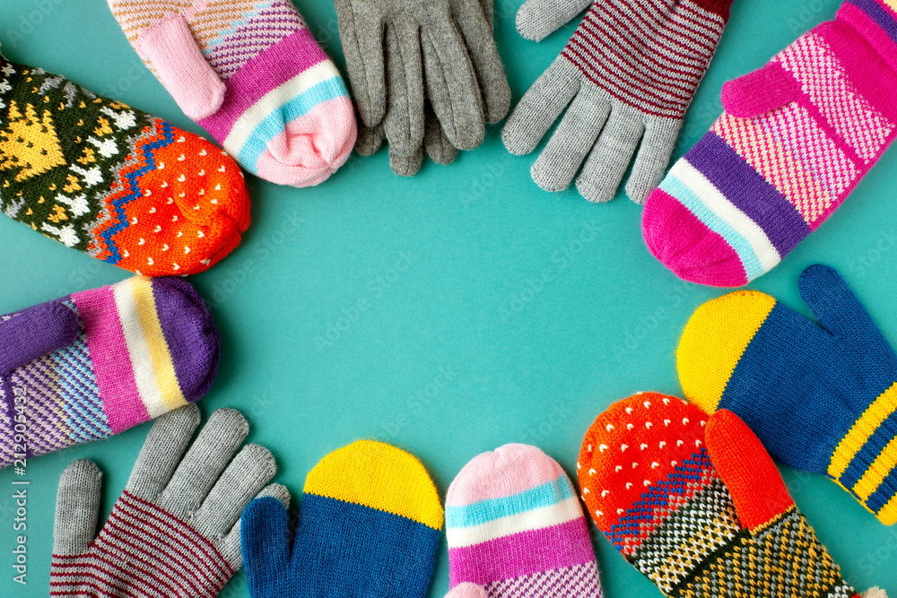 Mittens and gloves of different colors. View from above. Clothes for cold  autumn and winter in the form of mittens and gloves. Warm clothing on a  turquoise background. foto de Stock
