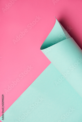 close-up view of rolled turquoise paper on creative pink background