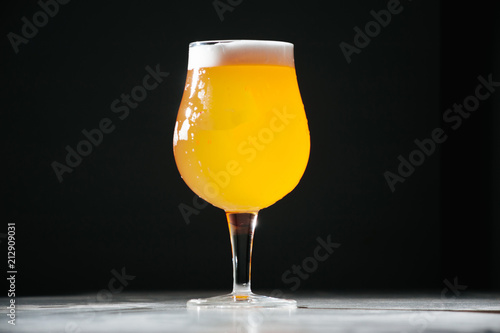 Glass beer with foam on black background with copyspace
