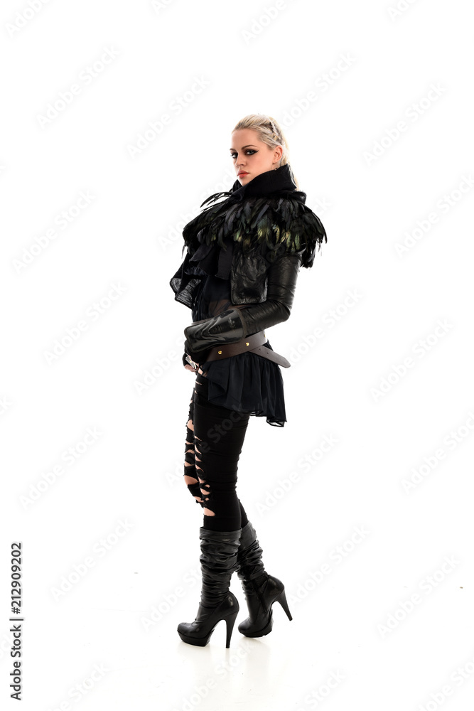 full length portrait of blonde girl wearing lack fantasy warrior outfit. standing pose wit bak to the camera. isolated on white studio background. full length portrait of blonde girl wearing lack fantasy warrior outfit. standing pose wit bak to the camera. isolated on white studio background.