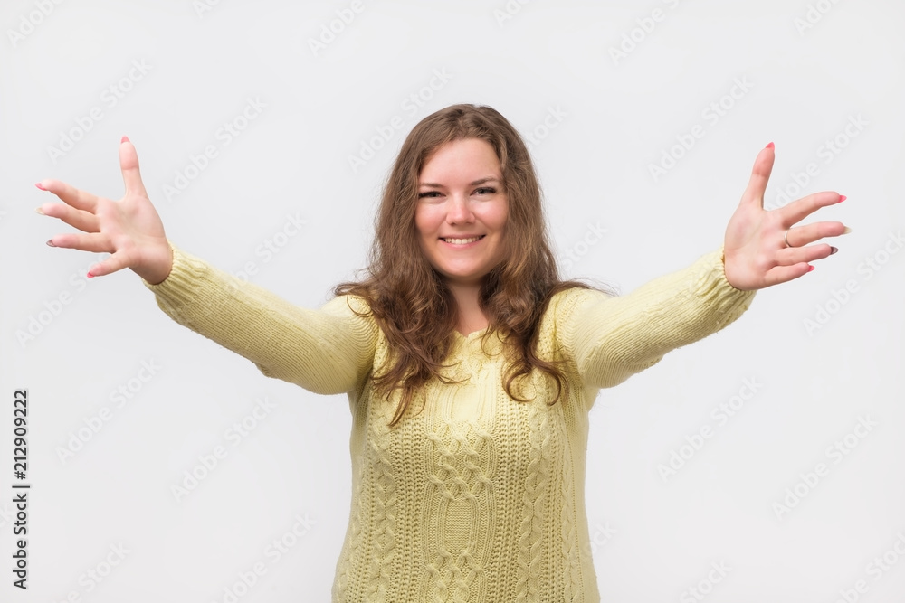 portrait of attractive smiling caucasian woman raised up arms hands at you. She is dressed in yellow sweater. Happy to welcome a friend or guest. I want to hug you. portrait of attractive smiling caucasian woman raised up arms hands at you. She is dressed in yellow sweater. Happy to welcome a friend or guest. I want to hug you.