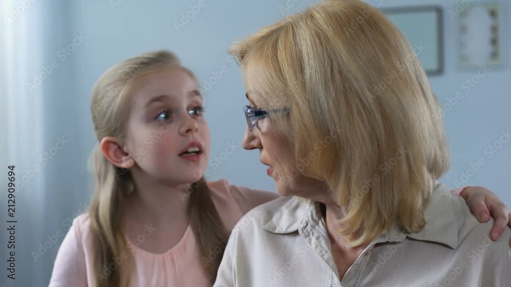 Little long haired girl whispering secret surprised grandmom, family connection Little long haired girl whispering secret surprised grandmom, family connection