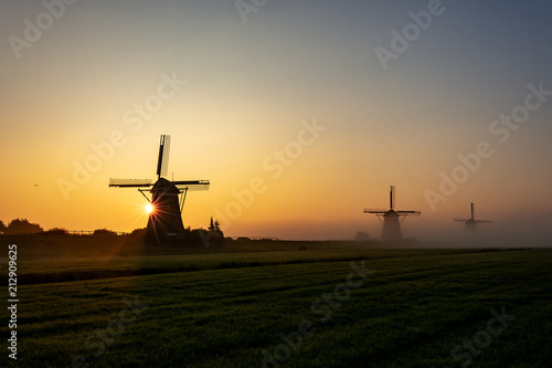 Three wind mills in the morning mist and the sun that comes through