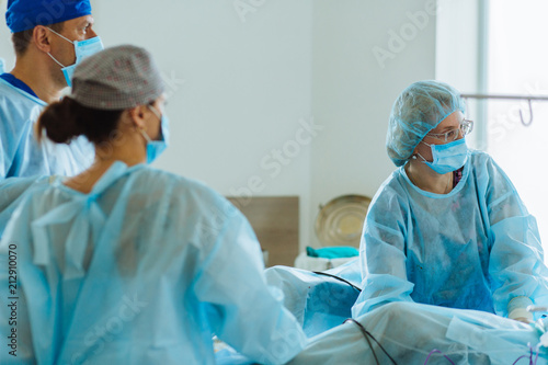 Surgeons team looks at monitors while preforming operation in hospital operating theater, male surgeon operating patient working with surgical laparoscopy instruments. Gynecology. Close up