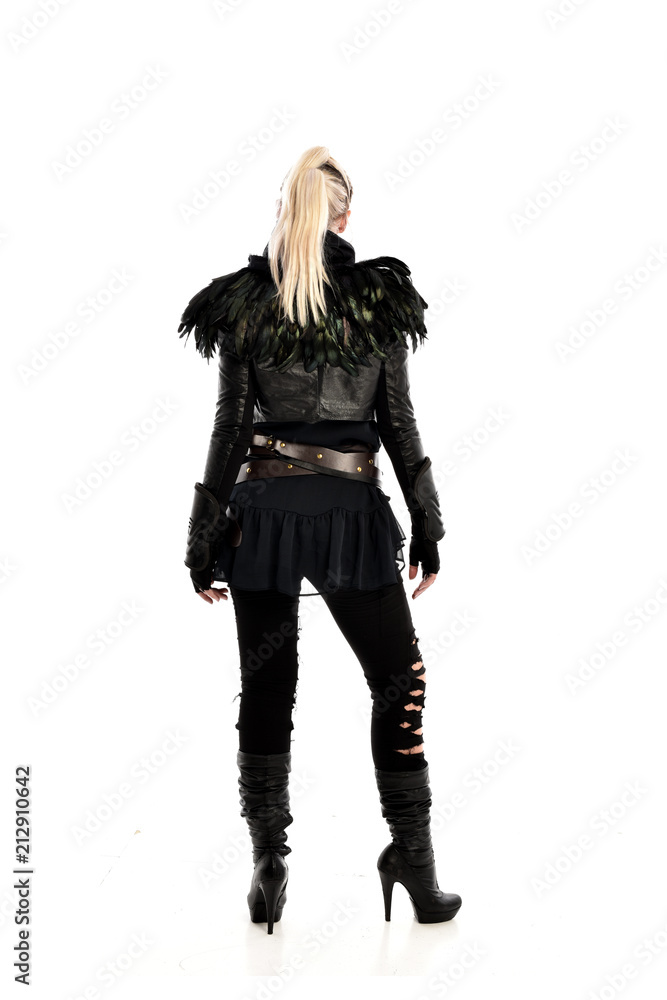 full length portrait of blonde girl wearing lack fantasy warrior outfit. standing pose wit bak to the camera. isolated on white studio background.