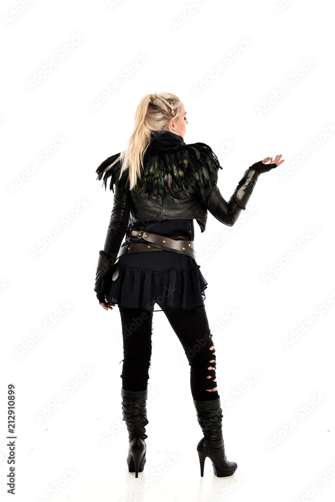 full length portrait of blonde girl wearing lack fantasy warrior outfit. standing pose wit bak to the camera. isolated on white studio background. full length portrait of blonde girl wearing lack fantasy warrior outfit. standing pose wit bak to the camera. isolated on white studio background.