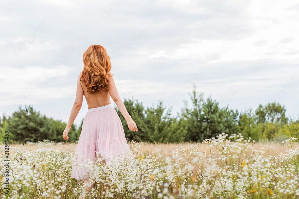 Flowers and romantic woman in the field. Lit evening sun, Beauty Romantic Girl Outdoors. Blowing Long Hair. Autumn. Glow Sun, Sunshine. Toned in warm colors Flowers and romantic woman in the field. Lit evening sun, Beauty Romantic Girl Outdoors. Blowing Long Hair. Autumn. Glow Sun, Sunshine. Toned in warm colors