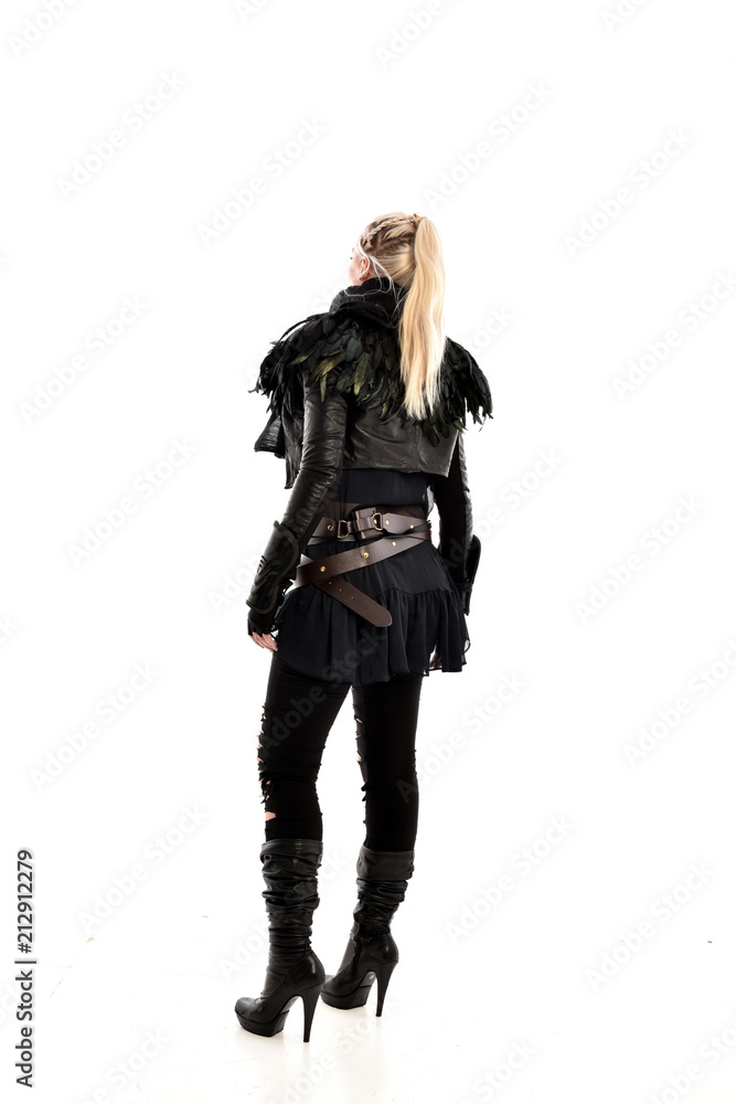full length portrait of blonde girl wearing lack fantasy warrior outfit. standing pose wit bak to the camera. isolated on white studio background. full length portrait of blonde girl wearing lack fantasy warrior outfit. standing pose wit bak to the camera. isolated on white studio background.