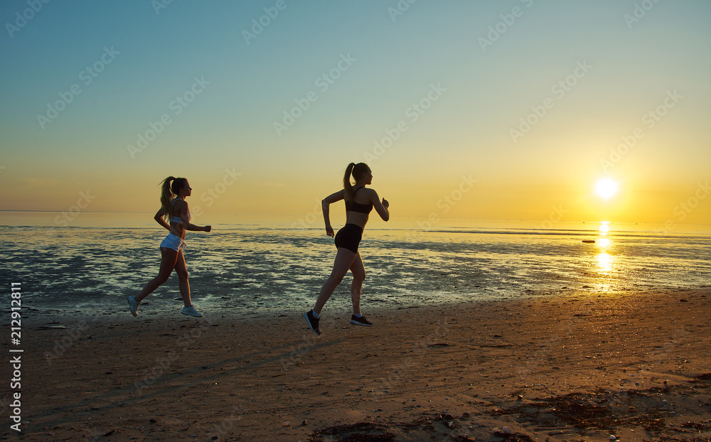 two girl running by the sea on the beach