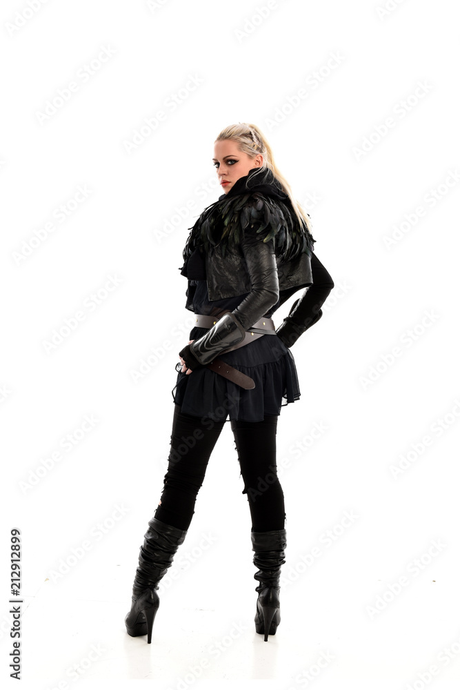 full length portrait of blonde girl wearing lack fantasy warrior outfit. standing pose wit bak to the camera. isolated on white studio background. full length portrait of blonde girl wearing lack fantasy warrior outfit. standing pose wit bak to the camera. isolated on white studio background.