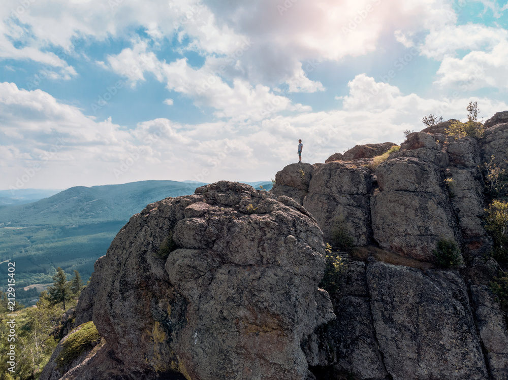 Man is standing on a mountain cliff and looks into the distance. amazing view
