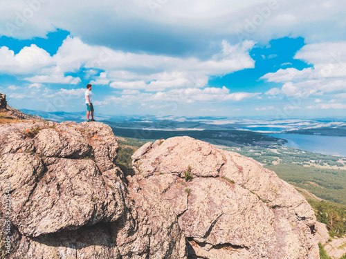 Man is standing on a mountain cliff and looks into the distance. amazing view photo