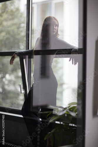 Attractive Female Standing Between Window Glass With Head Turned © Nektarstock
