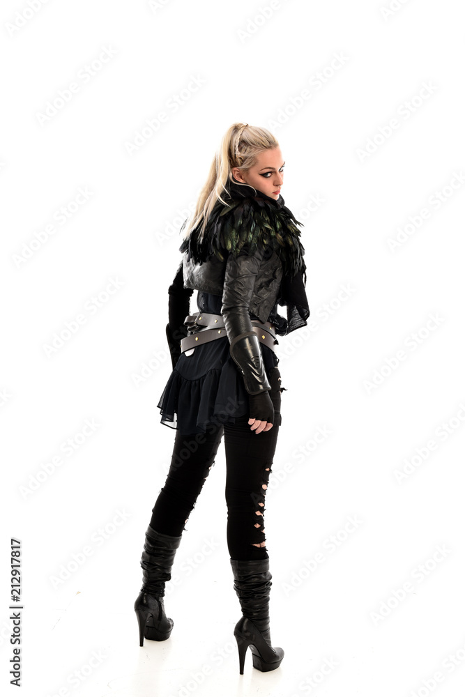 full length portrait of blonde girl wearing lack fantasy warrior outfit. standing pose wit bak to the camera. isolated on white studio background. full length portrait of blonde girl wearing lack fantasy warrior outfit. standing pose wit bak to the camera. isolated on white studio background.