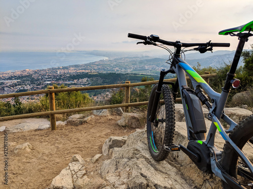 Electric mountain bike standing on top of mountain overlooking the ocean and valley near Barcelona Spain