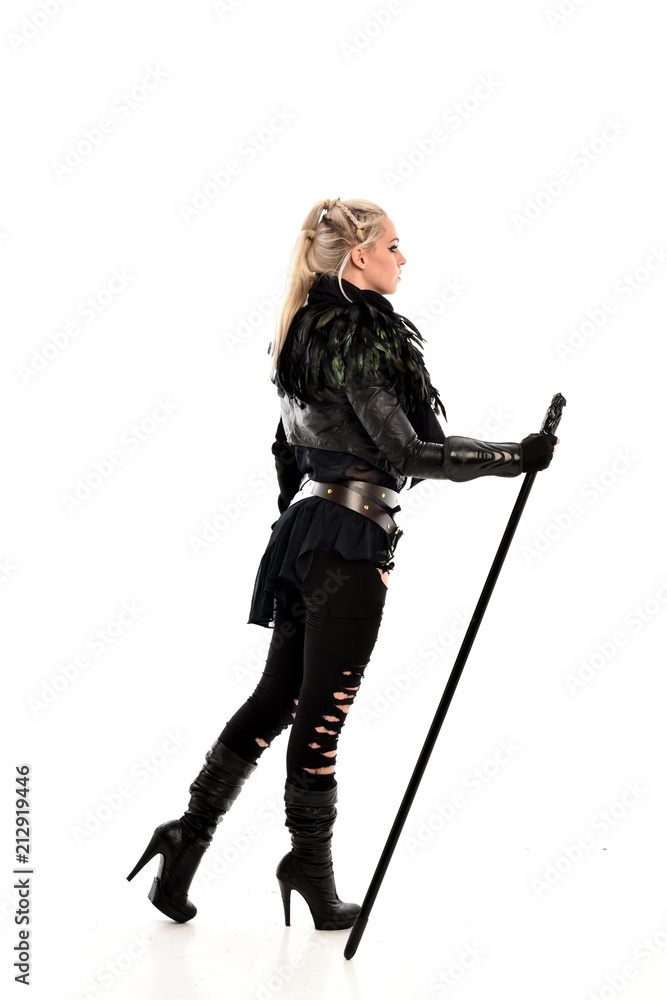 full length portrait of blonde girl wearing lack fantasy warrior outfit. standing pose wit bak to the camera. isolated on white studio background. full length portrait of blonde girl wearing lack fantasy warrior outfit. standing pose wit bak to the camera. isolated on white studio background.