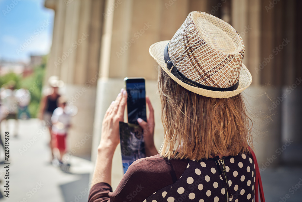 Female traveler in sunhat is taking a photo of using mobile phone.