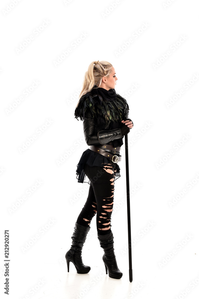 full length portrait of blonde girl wearing lack fantasy warrior outfit. standing pose wit bak to the camera. isolated on white studio background. full length portrait of blonde girl wearing lack fantasy warrior outfit. standing pose wit bak to the camera. isolated on white studio background.