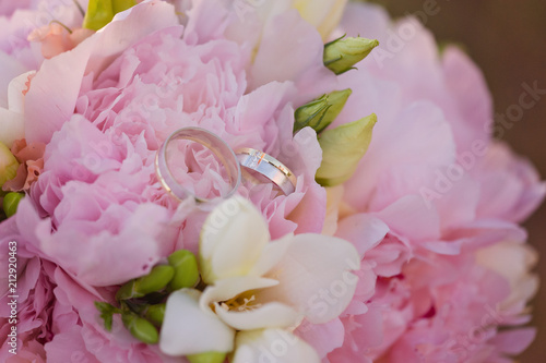 White gold wedding rings with stones on a pink wedding bouquet