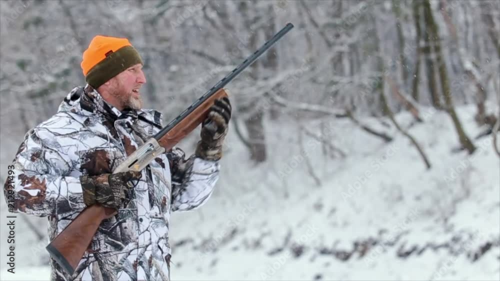 The man in camouflage charge a shotgun with cartridges, targets and shoots with a shotgun. 50 fps The man in camouflage charge a shotgun with cartridges, targets and shoots with a shotgun. 50 fps