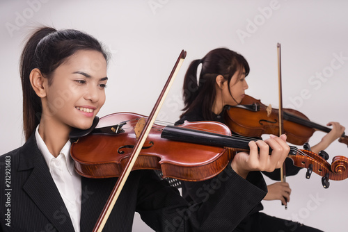 The lady with violin is playing song in front of the lady is playing viola,blurry light around.
