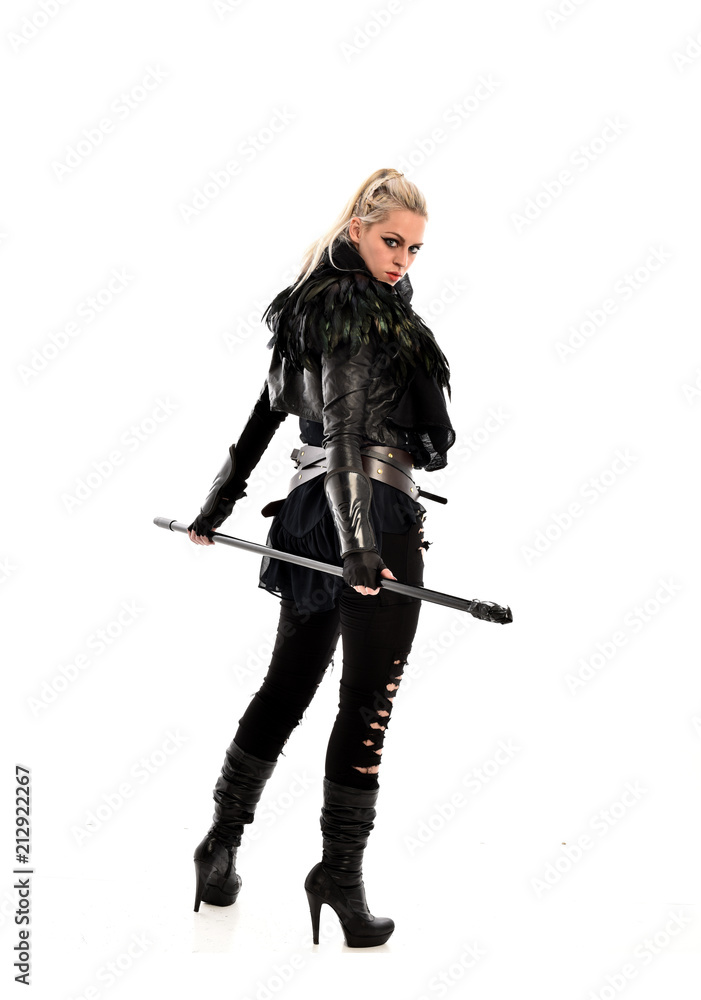 full length portrait of blonde girl wearing lack fantasy warrior outfit. standing pose wit bak to the camera. isolated on white studio background. full length portrait of blonde girl wearing lack fantasy warrior outfit. standing pose wit bak to the camera. isolated on white studio background.