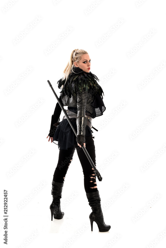 full length portrait of blonde girl wearing lack fantasy warrior outfit. standing pose wit bak to the camera. isolated on white studio background. full length portrait of blonde girl wearing lack fantasy warrior outfit. standing pose wit bak to the camera. isolated on white studio background.