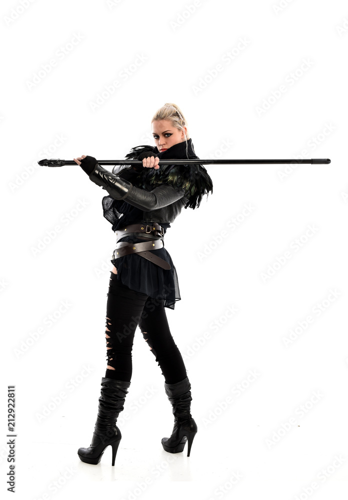 full length portrait of blonde girl wearing lack fantasy warrior outfit. standing pose wit bak to the camera. isolated on white studio background. full length portrait of blonde girl wearing lack fantasy warrior outfit. standing pose wit bak to the camera. isolated on white studio background.