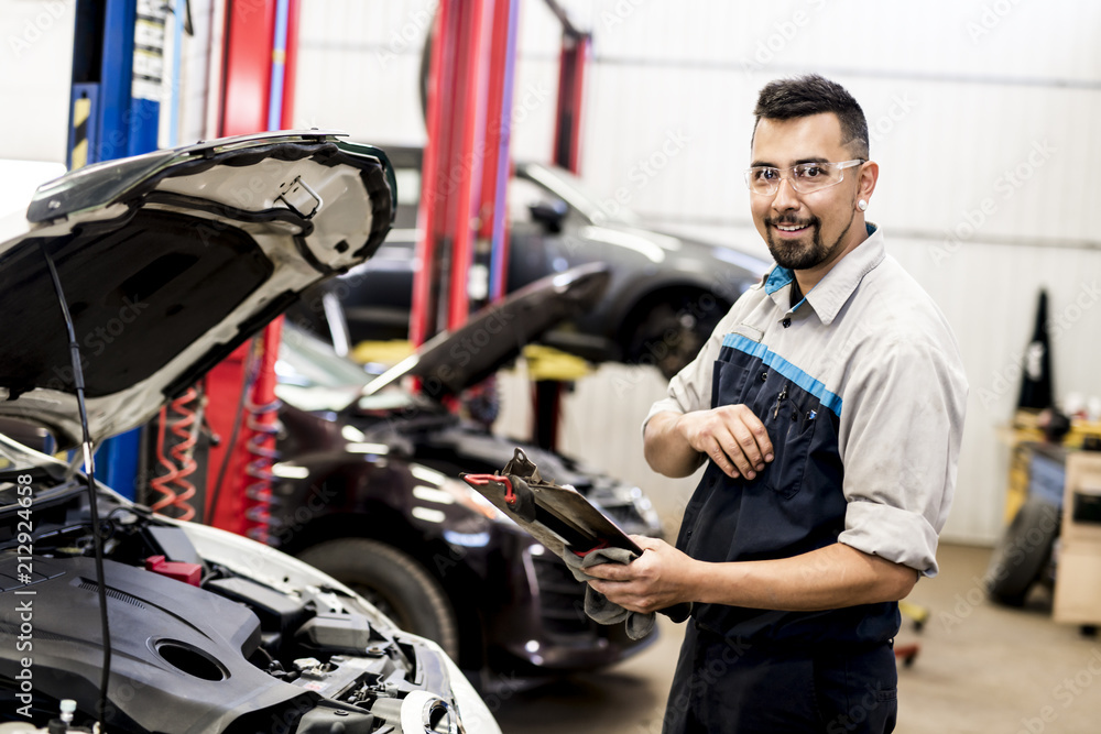 Handsome mechanic job in uniform working on car Handsome mechanic job in uniform working on car
