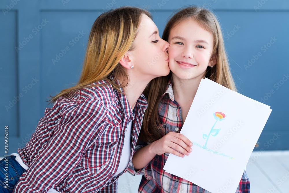 kid creativity and art. girl showing a drawing of flower. child leisure hobby and self expression. loving mom kissing her daughter kid creativity and art. girl showing a drawing of flower. child leisure hobby and self expression. loving mom kissing her daughter