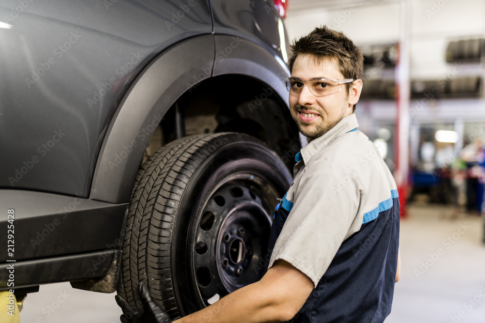 Handsome mechanic job in uniform working on car Handsome mechanic job in uniform working on car