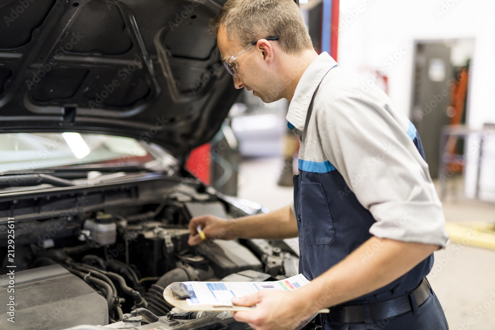 Handsome mechanic job in uniform working on car Handsome mechanic job in uniform working on car