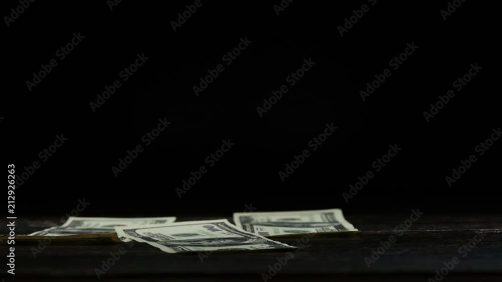 US dollar bills falling down,side view. 100 US dollar banknotes flipping down to old wooden table with black background ,hd slow motion video. US dollar bills falling down,side view. 100 US dollar banknotes flipping down to old wooden table with black background ,hd slow motion video.