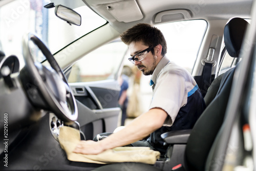 Man at work cleaning inside automobile at car wash