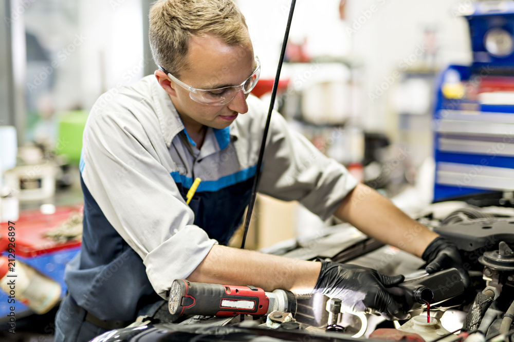 Handsome mechanic job in uniform working on car Handsome mechanic job in uniform working on car