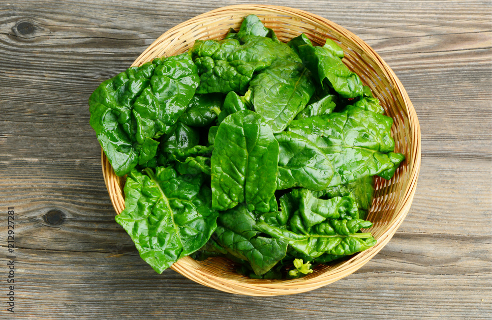 Benefits of Spinach leaves in basket on wooden floor. Benefits of Spinach leaves in basket on wooden floor.