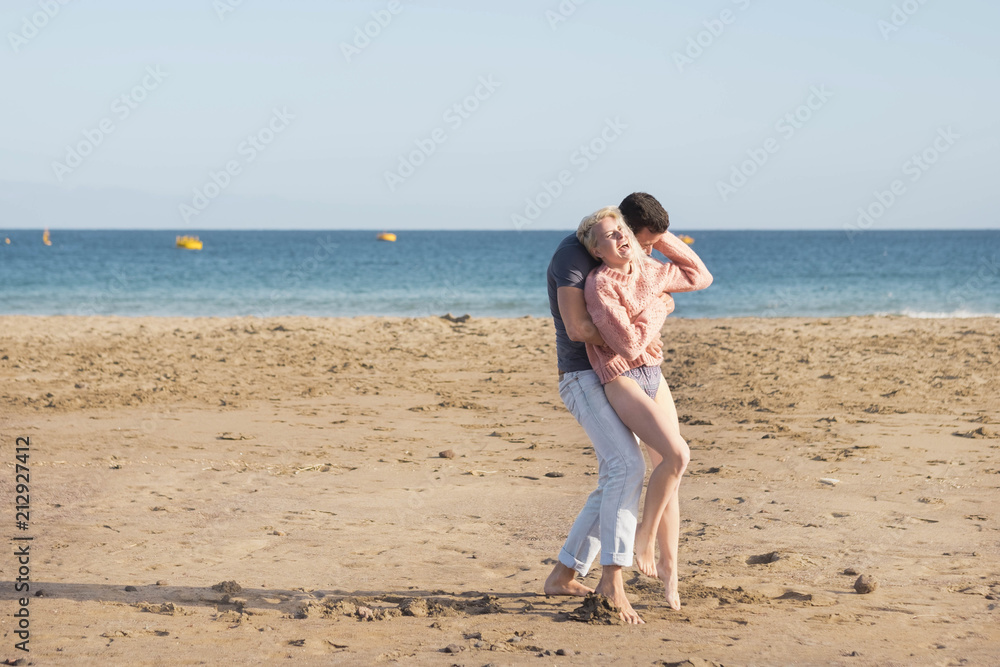 nice caucasian couple in vacation leisure outdoor. enjoy and smile in love together playing and hugging full of lovely thoughts. beach place and ocean horizon colored in background
