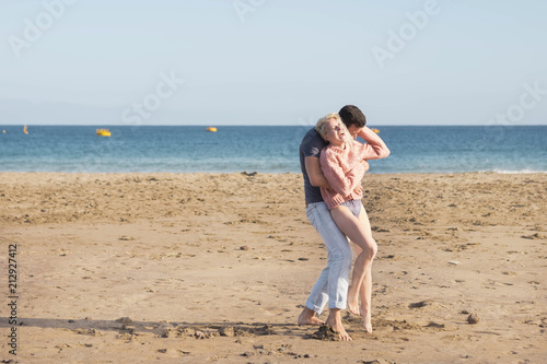 nice caucasian couple in vacation leisure outdoor. enjoy and smile in love together playing and hugging full of lovely thoughts. beach place and ocean horizon colored in background © simona