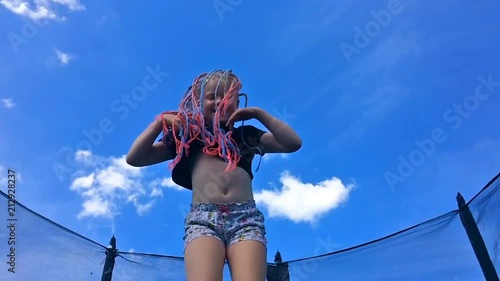 carefree childhood, happy summer. beautiful girl with African pigtails jumping on a trampoline - slow motion photo