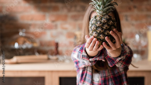 fresh organic natural fruit for kids balanced diet. little girl holding a pineapple
